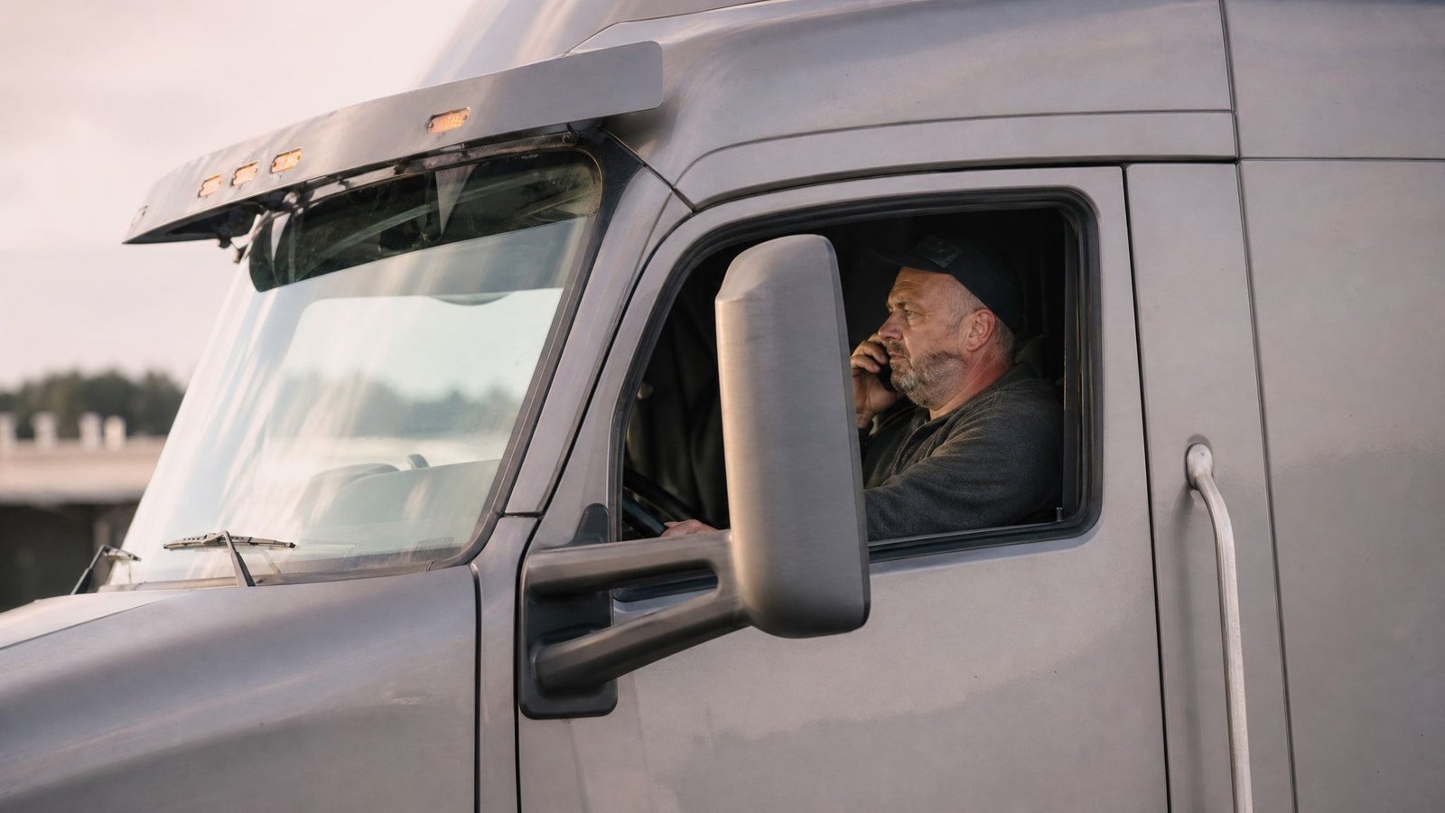 Truck driver on a phone call in the cab of his parked semi