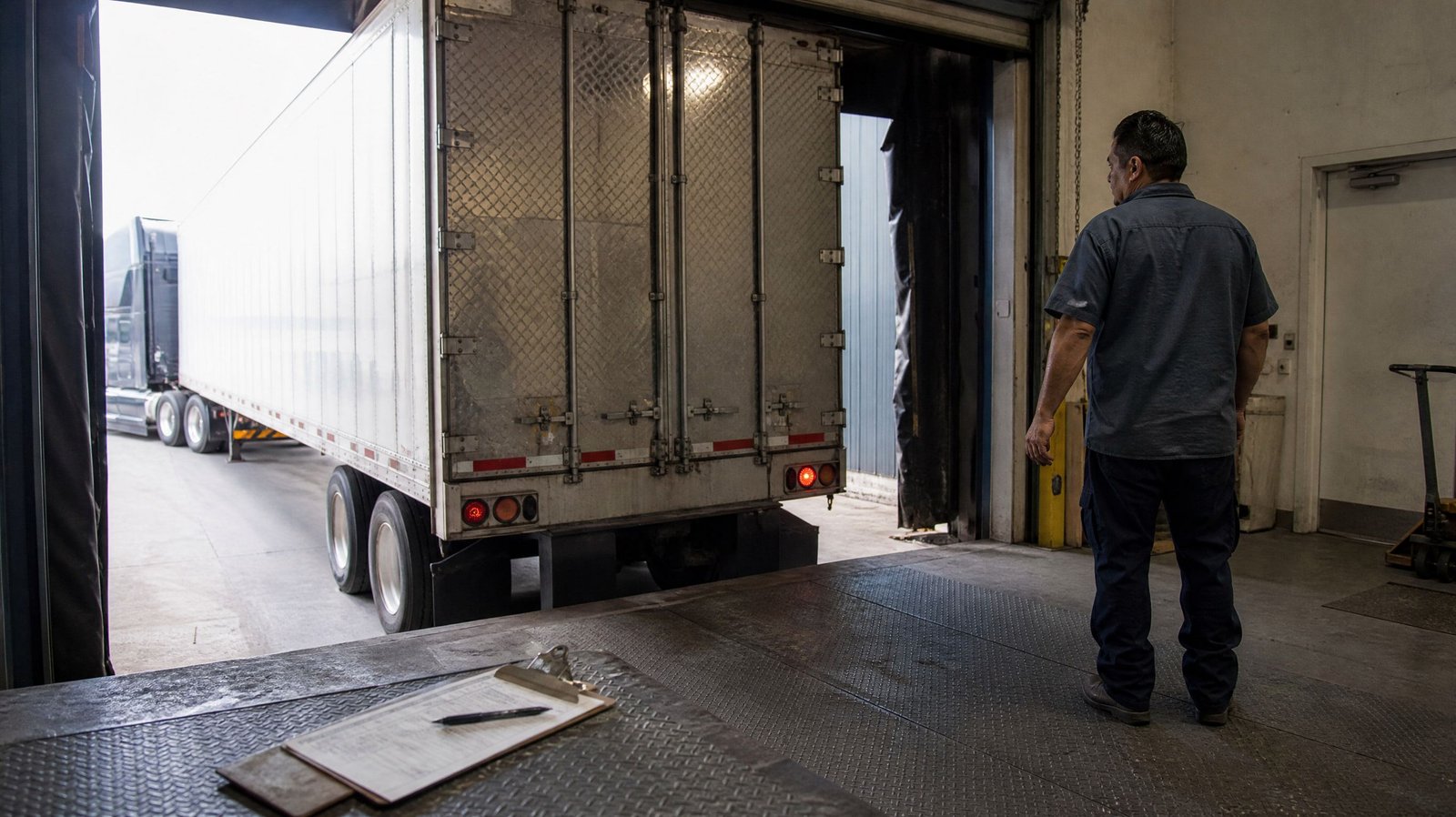 Bill of lading on a clipboard at a warehouse loading dock with a trailer backed in